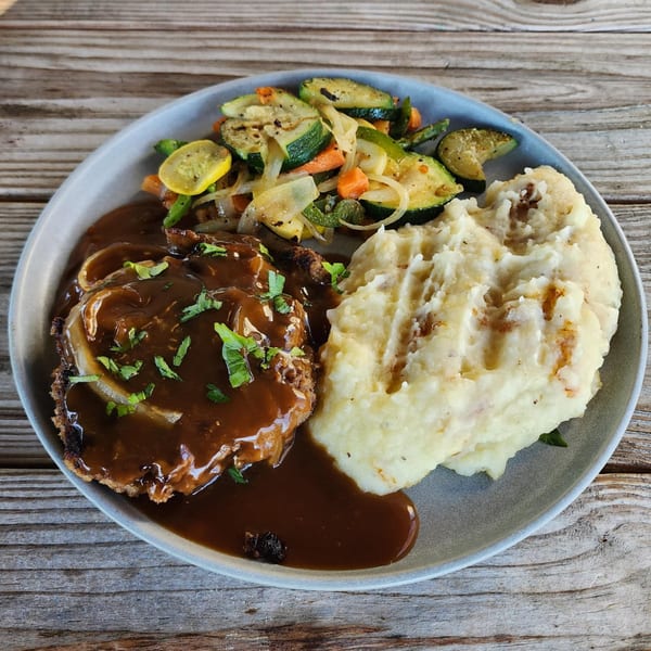 Meatloaf with gravy, mashed potatoes, and grilled vegetables on a gray plate at The Tavern at Sugar Hill.