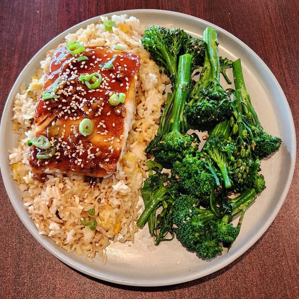 Teriyaki salmon with sesame seeds and scallions, served with fried rice and broccolini.